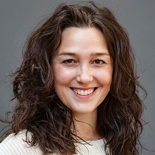 Mercè Ribot wearing a white jumper and smiling directly at the camera.